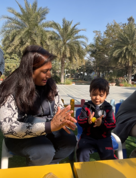 Toddler making a yellow hand print with a teacher