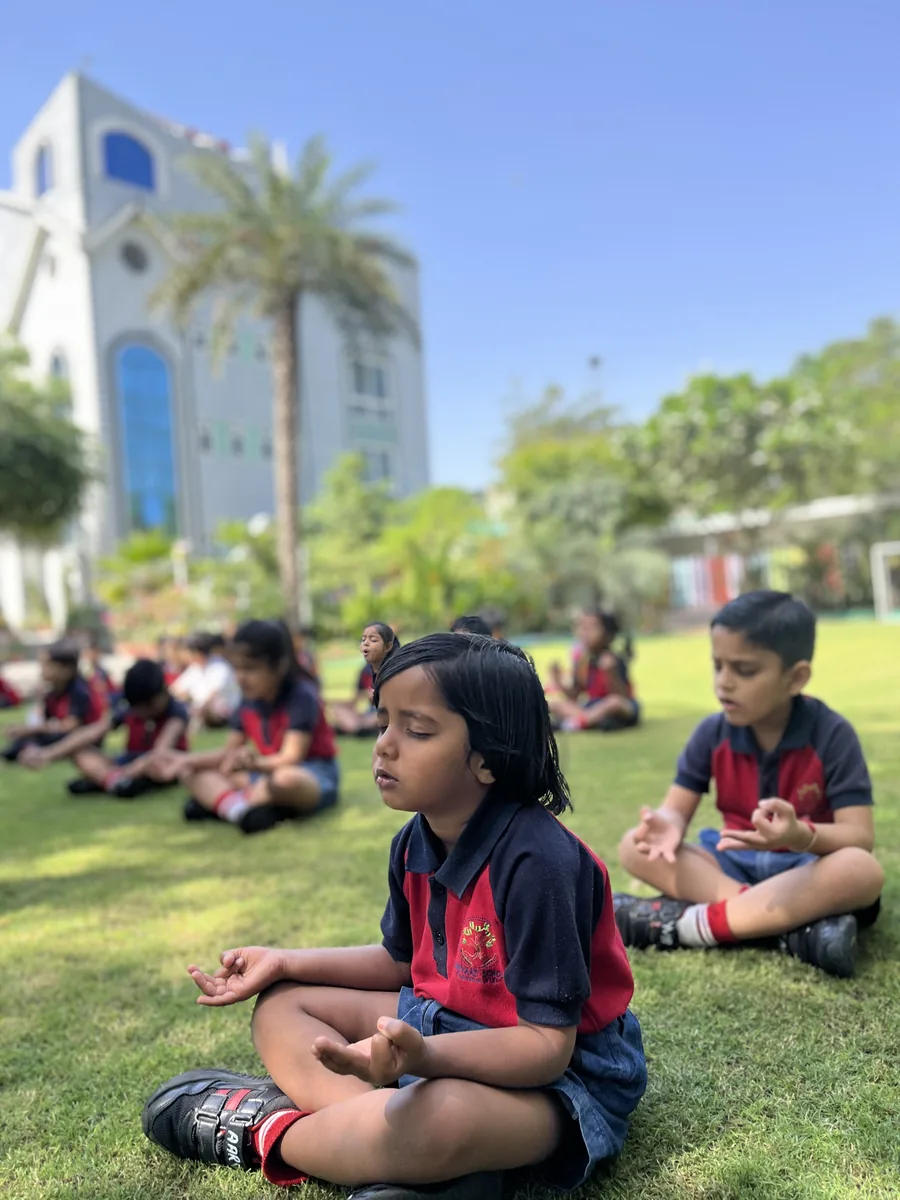 Children doing yoga stretches on the campus lawn