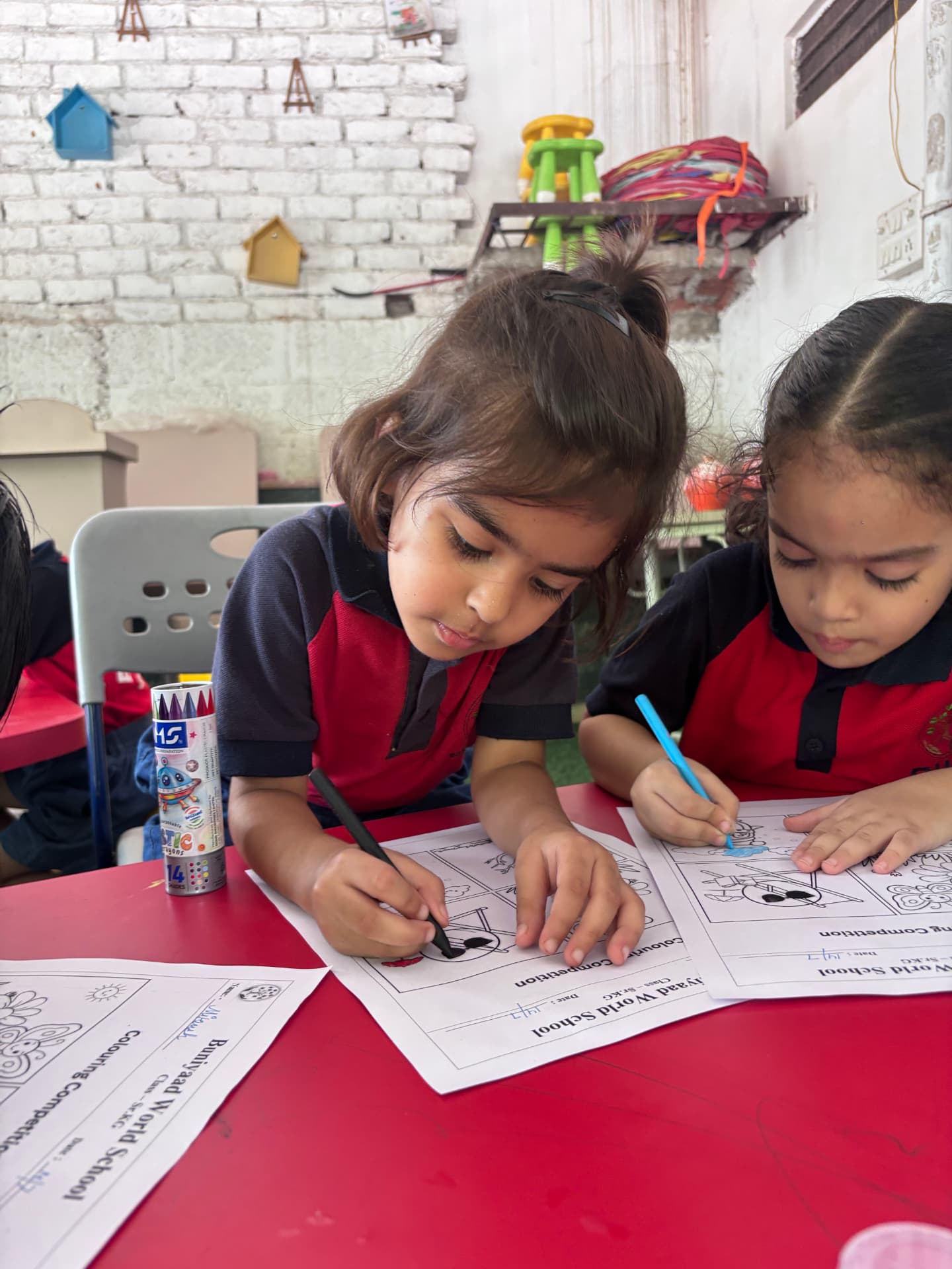 Two students colouring their worksheets side by side in class