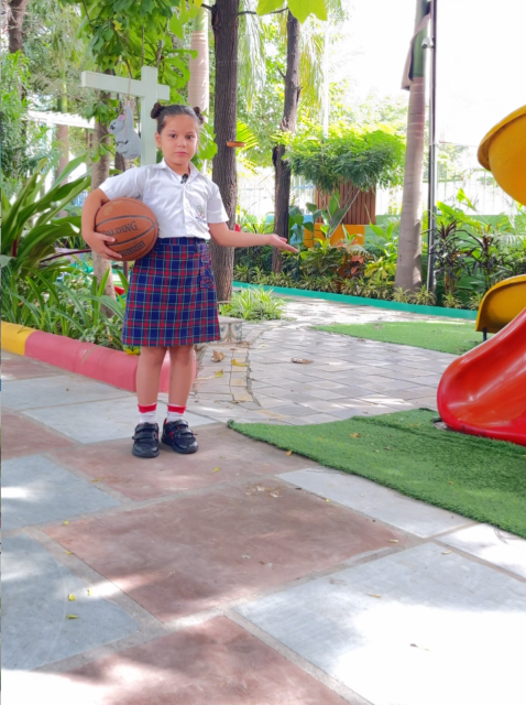 A girl holding a basketball on the outdoor sports area