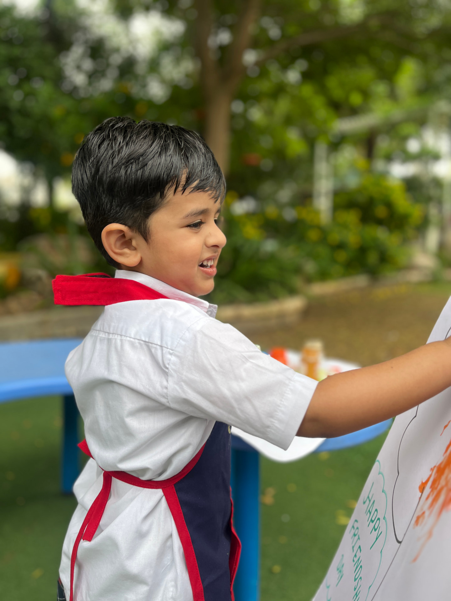 A young boy painting a colourful poster outdoors